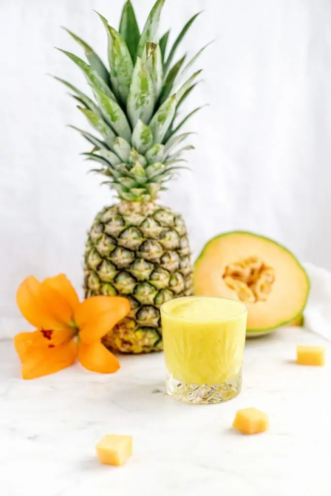 pineapple fruit smoothie beside orange petaled flower